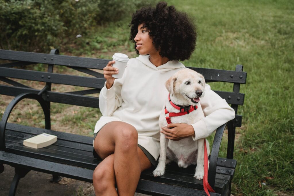 relaxed black woman drinking coffee near dog